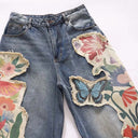 Vaqueros desgastados con borlas y campana