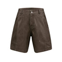 A pair of brown paneled vegan leather shorts with a zipper fly and knee length cut.
