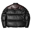 Black leather jacket on a textured surface with a hat in the background